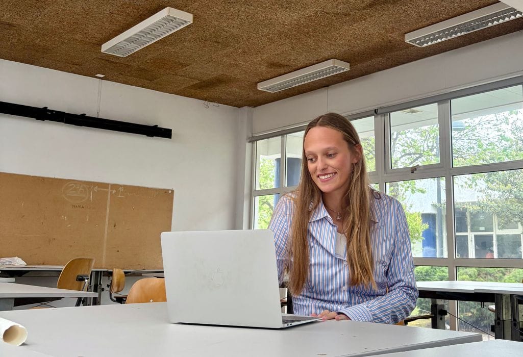 Debora Madile, fundadora da A Arquiteta da tua Marca enquanto trabalha no computador num estúdio da Faculdade de Arquitetura