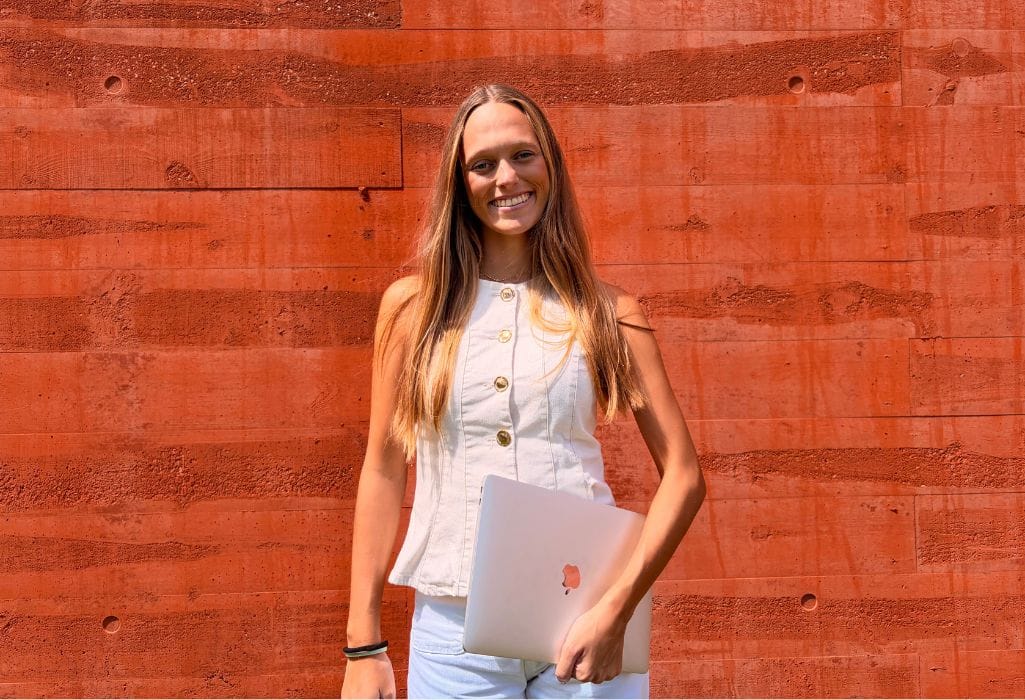 Debora Madile, fundadora da A Arquiteta da tua Marca e especialista em Marketing Digital aplicado à Arquitetura, a sorrir com um portátil na mão.
