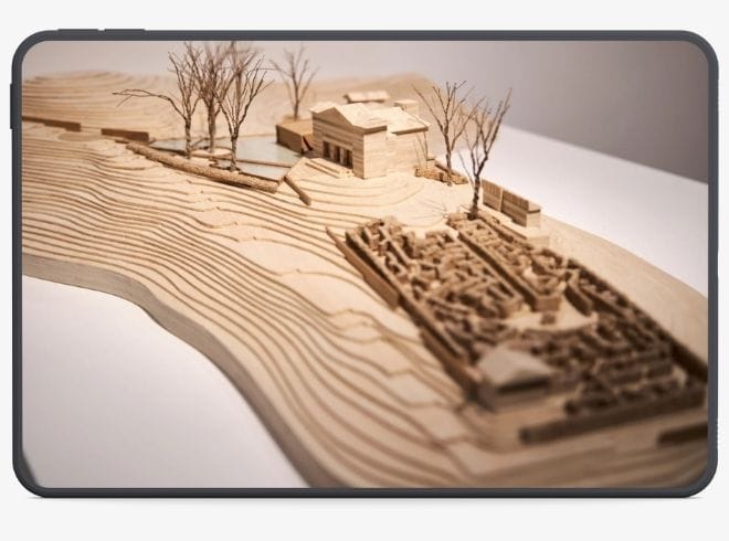 Maquete de arquitetura apresentada num ecrã de tablet, representando a transição do trabalho físico de um atelier para uma estratégia de marketing digital forte.